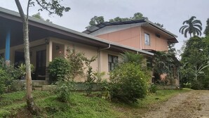 Een huis met twee verdiepingen, een overdekte veranda en een tuin.