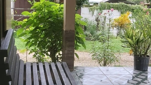 Een overdekt terras met een bank en plantenpotten.