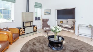 Ein modernes Wohnzimmer mit Kamin, Sitzecke und einem Glastisch mit Blumen.
