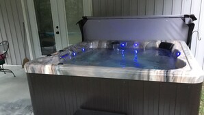 A hot tub with a built-in seat and step, positioned on a patio. - Secluded Retreat With hot tub ideal to fish and relax on private pond (Orangeburg)