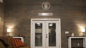 A room with a wooden wall, a double door, two side tables with lamps, a sofa, and a bench. - Secluded Retreat With hot tub ideal to fish and relax on private pond (Orangeburg)