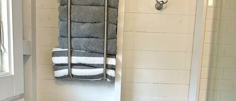 Un baño con un inodoro blanco, un perchero con toallas dobladas y una zona de ducha.