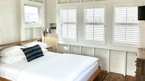 Ein Schlafzimmer mit einem hölzernen Bett, weißen Wänden und einer schrägen Decke.