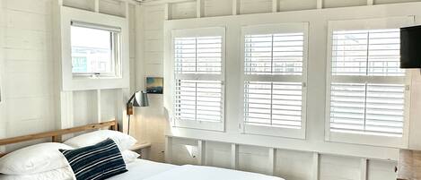 Un dormitorio con cama de madera, paredes blancas y techo inclinado.