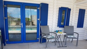A covered outdoor area with a pool, two wicker chairs, a small table, and a trash bin. - Stunning terraced Logcabin House with pool  (Saint Martin)