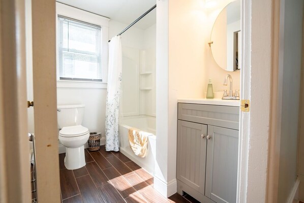 A bathroom with a toilet, shower, and vanity.