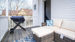 Eine überdachte Veranda mit einem Rattangeflechtssofa und einem Grill.