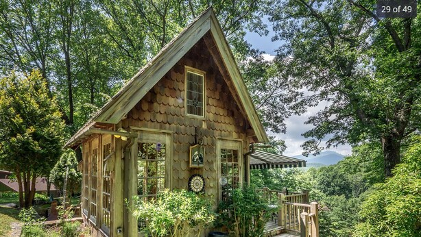 Eine Holzhütte mit geneigtem Dach, einer Veranda und einer kleinen Terrasse.