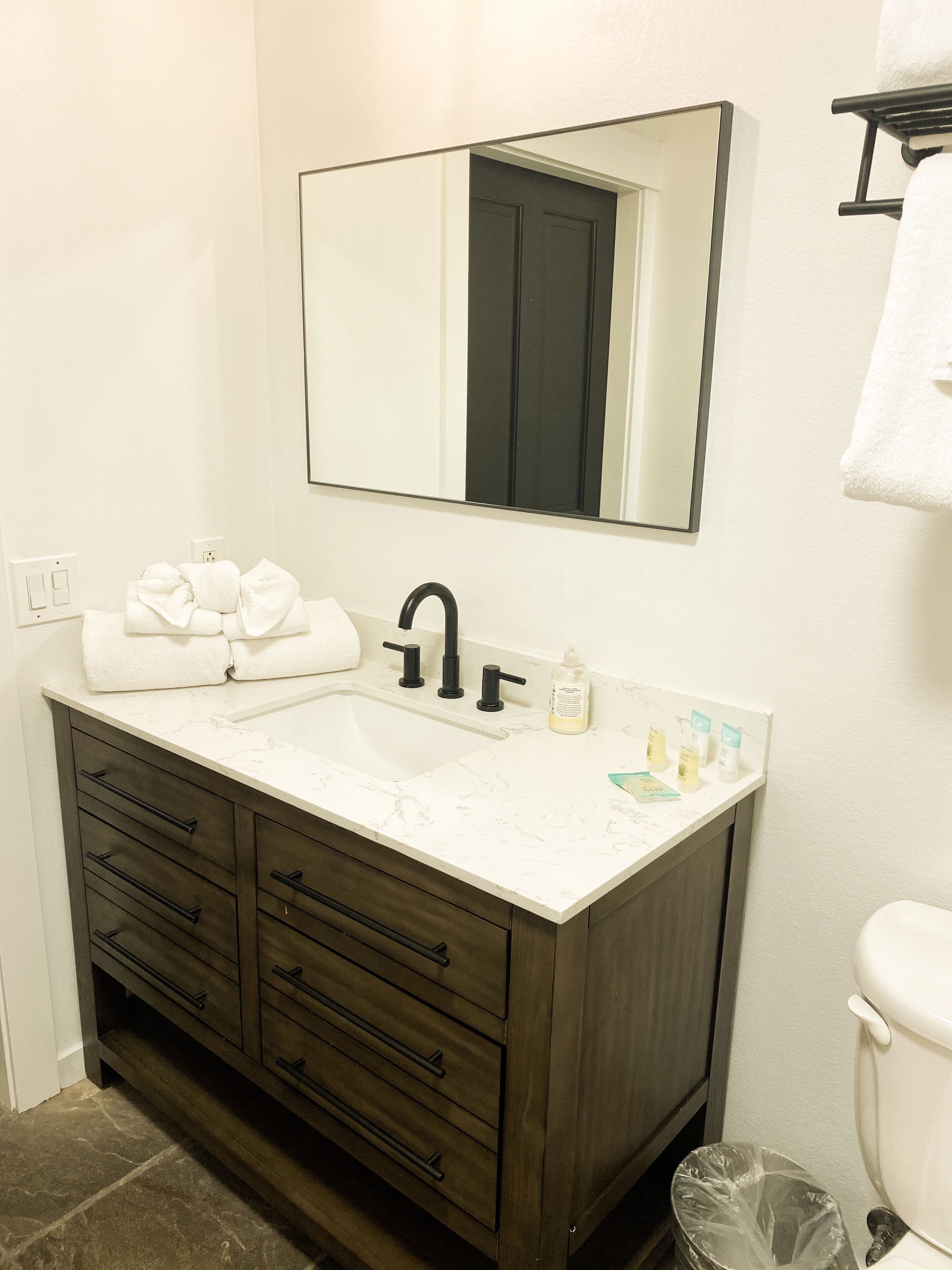 A bathroom with a white sink, dark wooden vanity, and a mirror above the sink.