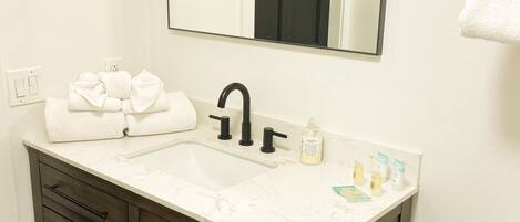 A bathroom with a white sink, dark wooden vanity, and a mirror above the sink.