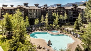 A resort with a large pool, multiple buildings with balconies, and a mountainous backdrop.