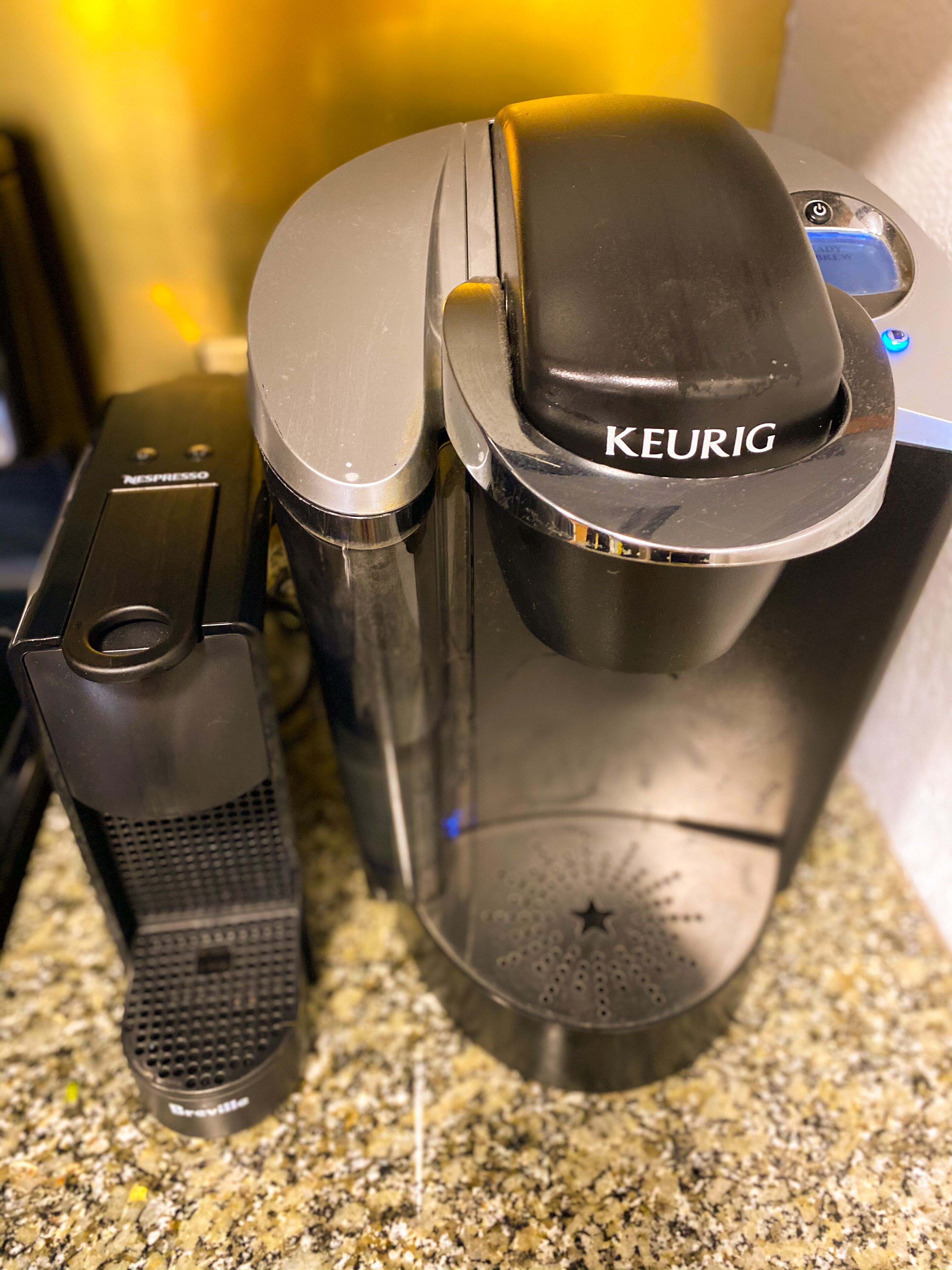 Eine Kaffeemaschine von Keurig mit Kapselhalter und Tropfschale auf einer Granitarbeitsplatte.