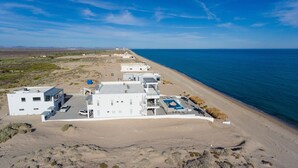A coastal hotel with multiple buildings, a parking area, and a beach. - Luxury Beachfront Six Palms Villas # 2 (puerto penasco)