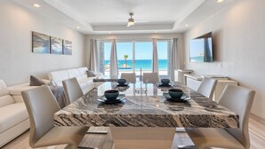 A modern dining area with a marble table, white chairs, and a view of the ocean. - Luxury Beachfront Six Palms Villas # 2 (puerto penasco)
