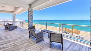 A covered outdoor area with wicker furniture, a pool, and a view of the beach and ocean. - Luxury Beachfront Six Palms Villas # 2 (puerto penasco)