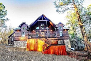 A log cabin with a stone foundation, a wooden deck, and a staircase leading to the entrance. - Lucky Rooster 3BD/3BA Sleeps 13/NEW Slides/Separate Game Room/Pool Table/Firepit (Broken Bow)