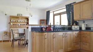 Uma cozinha com armários de madeira, um espaço de jantar com mesa e cadeiras, e uma janela com cortinas.