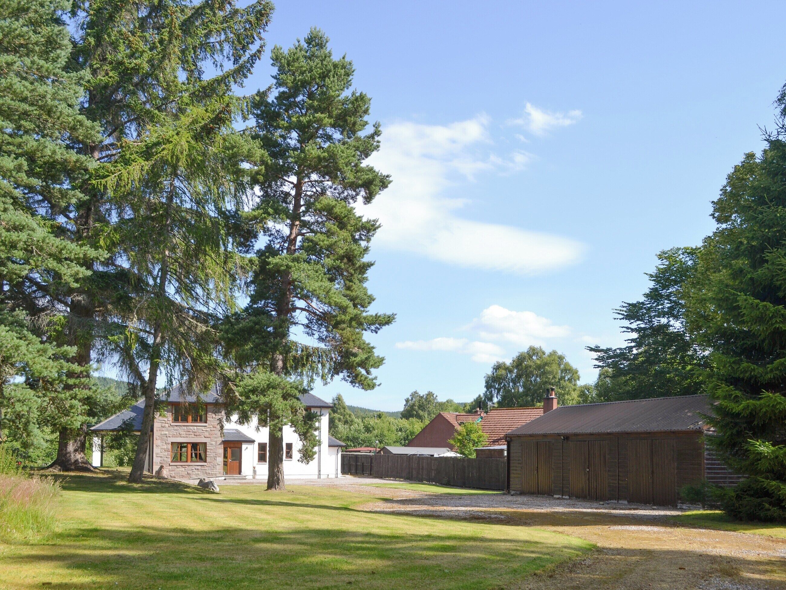 Une propriété rurale comprenant une maison en pierre, une grange en bois et un grand arbre.