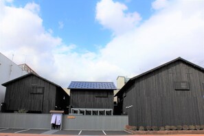 A row of three large, dark wooden buildings with a flat roof, likely used for commercial purposes. - Ishitei furano (Furano)