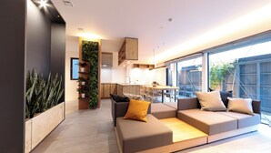 A modern living room with a sectional sofa, a coffee table, and a vertical garden. - Ishitei furano (Furano)