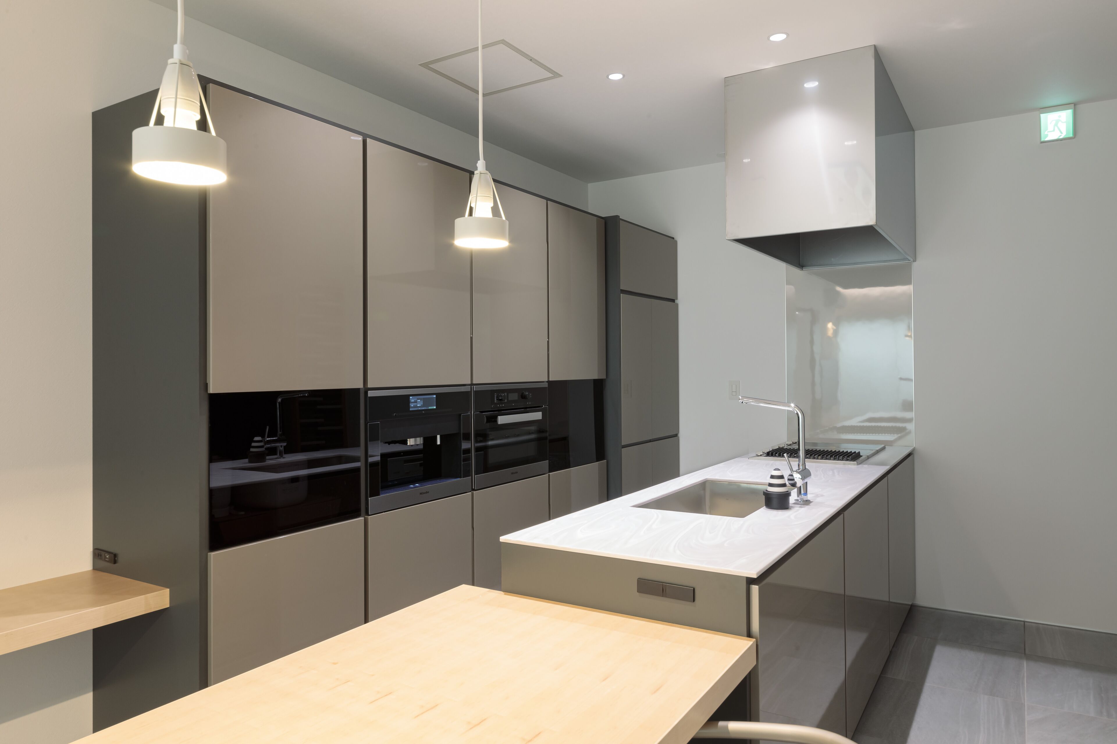 A modern kitchen with built-in appliances, a wooden countertop, and pendant lighting.