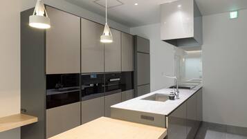Una cocina moderna con electrodomésticos integrados, encimera de madera e iluminación colgante.