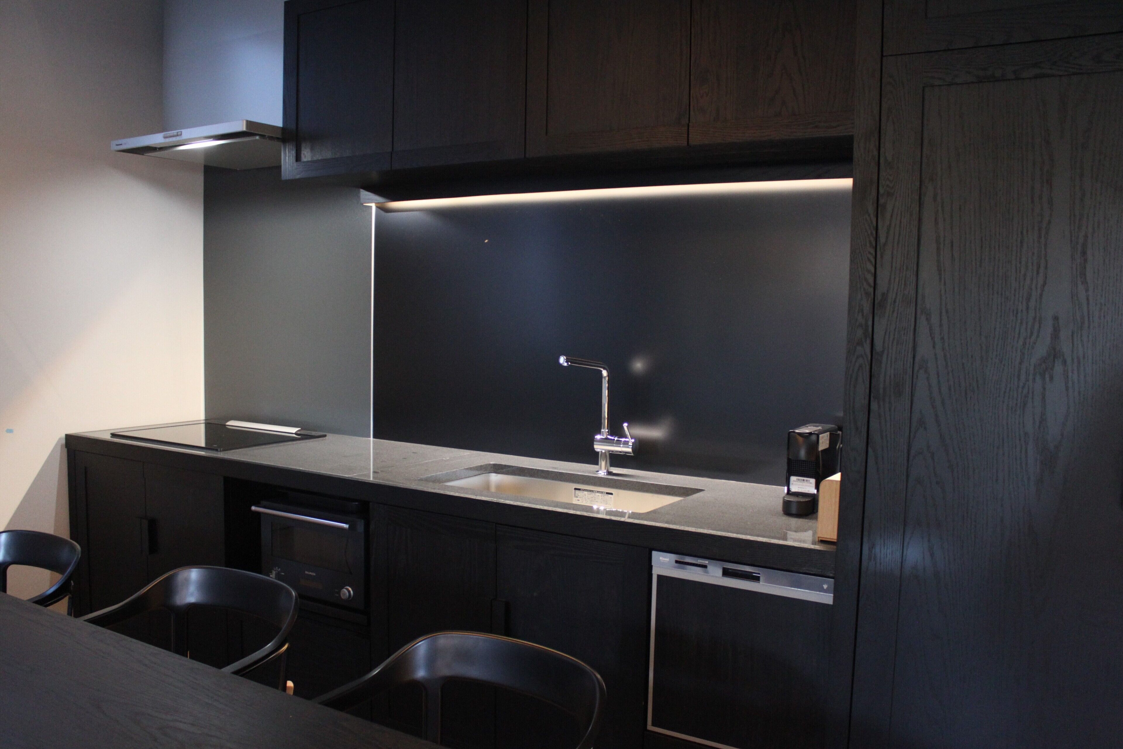 A compact kitchen with a modern design, featuring a stainless steel sink, a built-in oven, and a dishwasher.