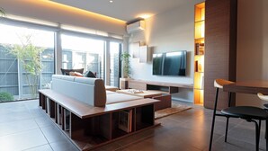 A modern living room with a sofa, TV, and built-in shelves. - Ishitei furano (Furano)