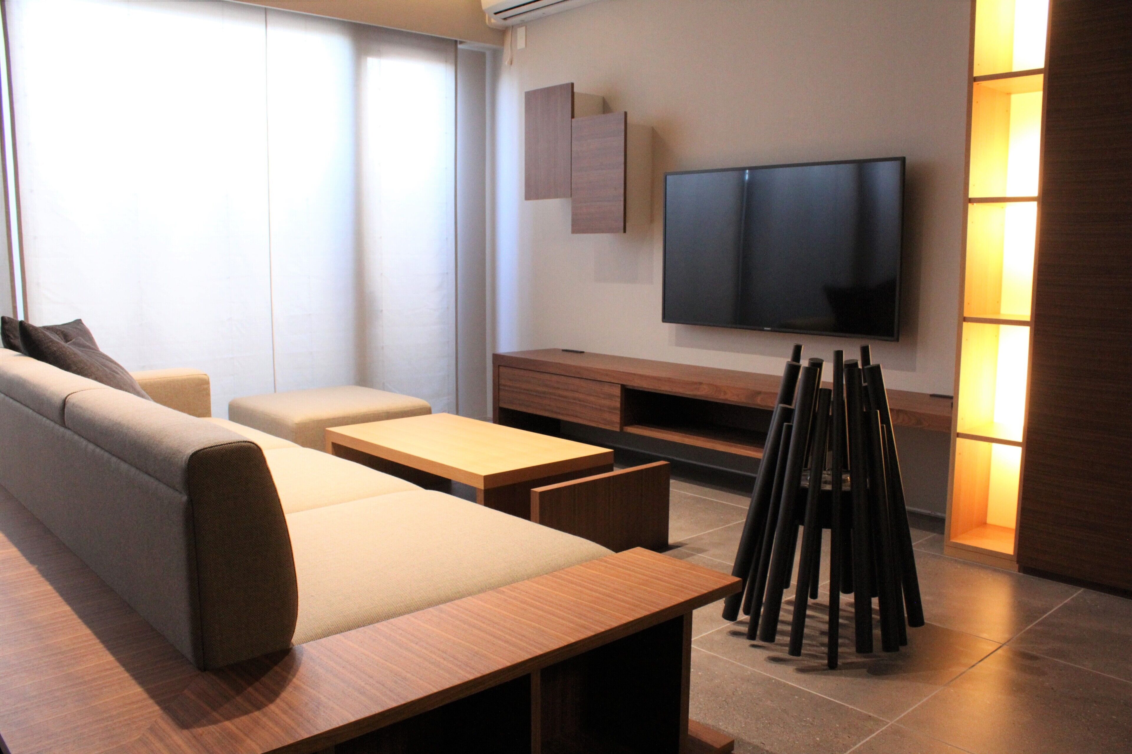 A modern living room with a sofa, a coffee table, and a TV mounted on the wall.