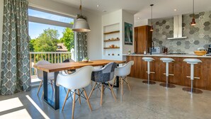 A modern kitchen with a wooden table, white chairs, and a bar area.