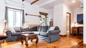 Un soggiorno con un divano grigio, un tavolino in legno e un pavimento di legno.