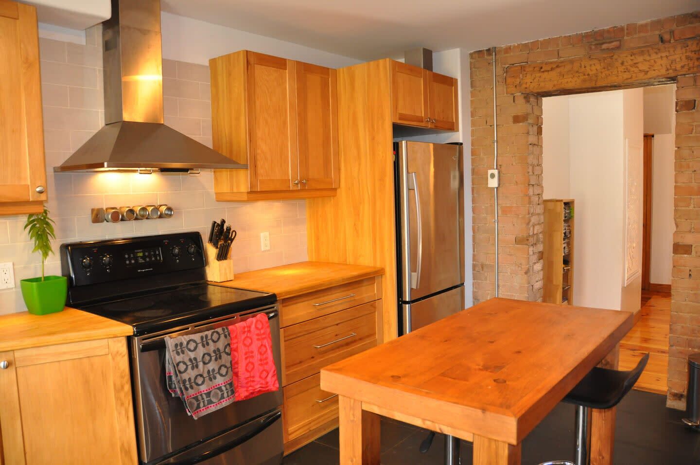 A modern kitchen with wooden cabinets, a stainless steel stove, and a refrigerator.