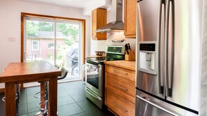 Una cucina moderna con elettrodomestici in acciaio inossidabile, mobili in legno e una porta scorrevole in vetro che dà su un patio.