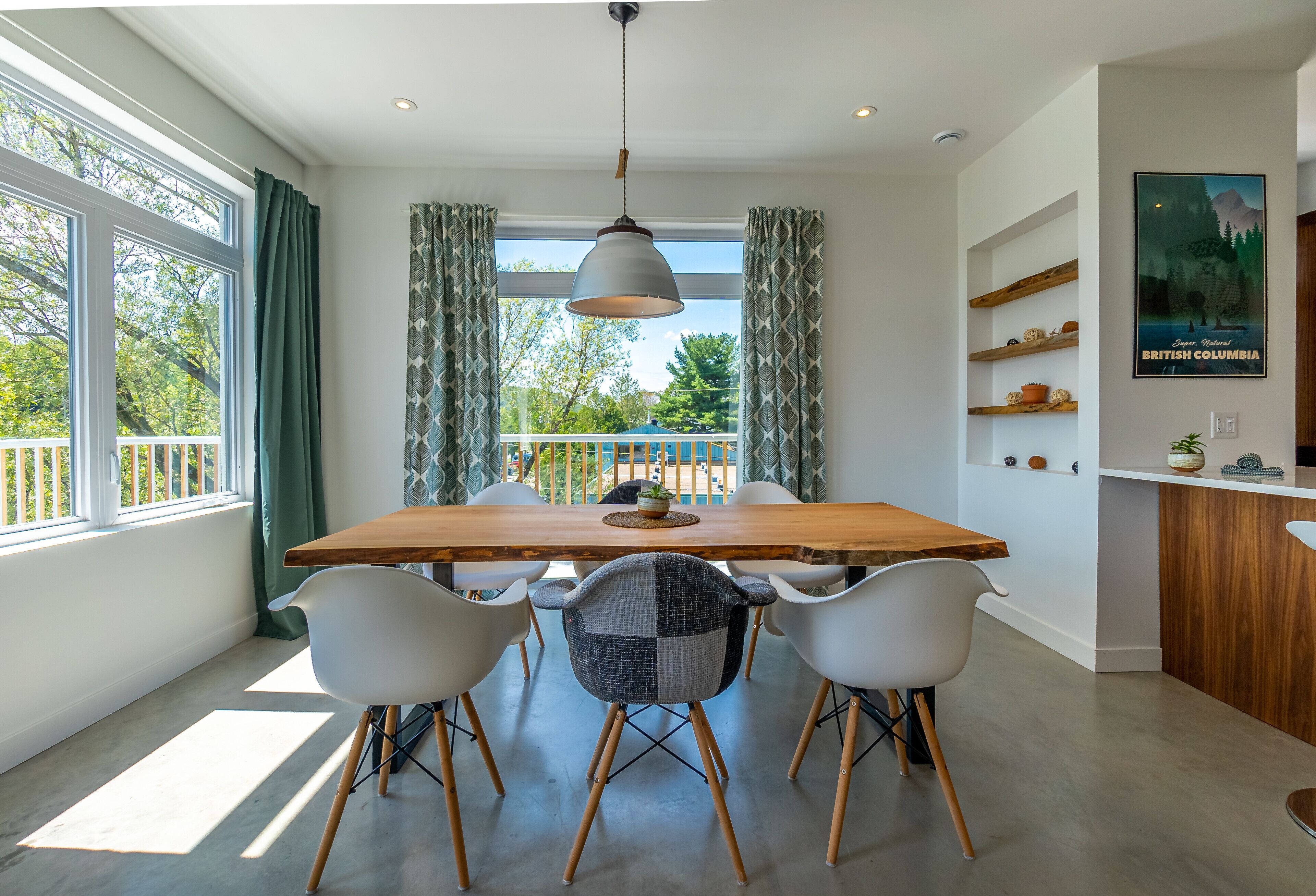 A dining area with a wooden table, six chairs, and a hanging light fixture.