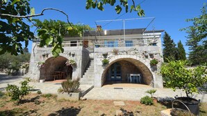 A stone building with two arched entrances and a balcony with potted plants. - Studio apartment Depope 1 (Skrbčići)
