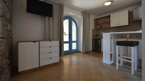 A kitchen with white cabinets, a blue door, and a tiled floor. - Studio apartment Depope 1 (Skrbčići)
