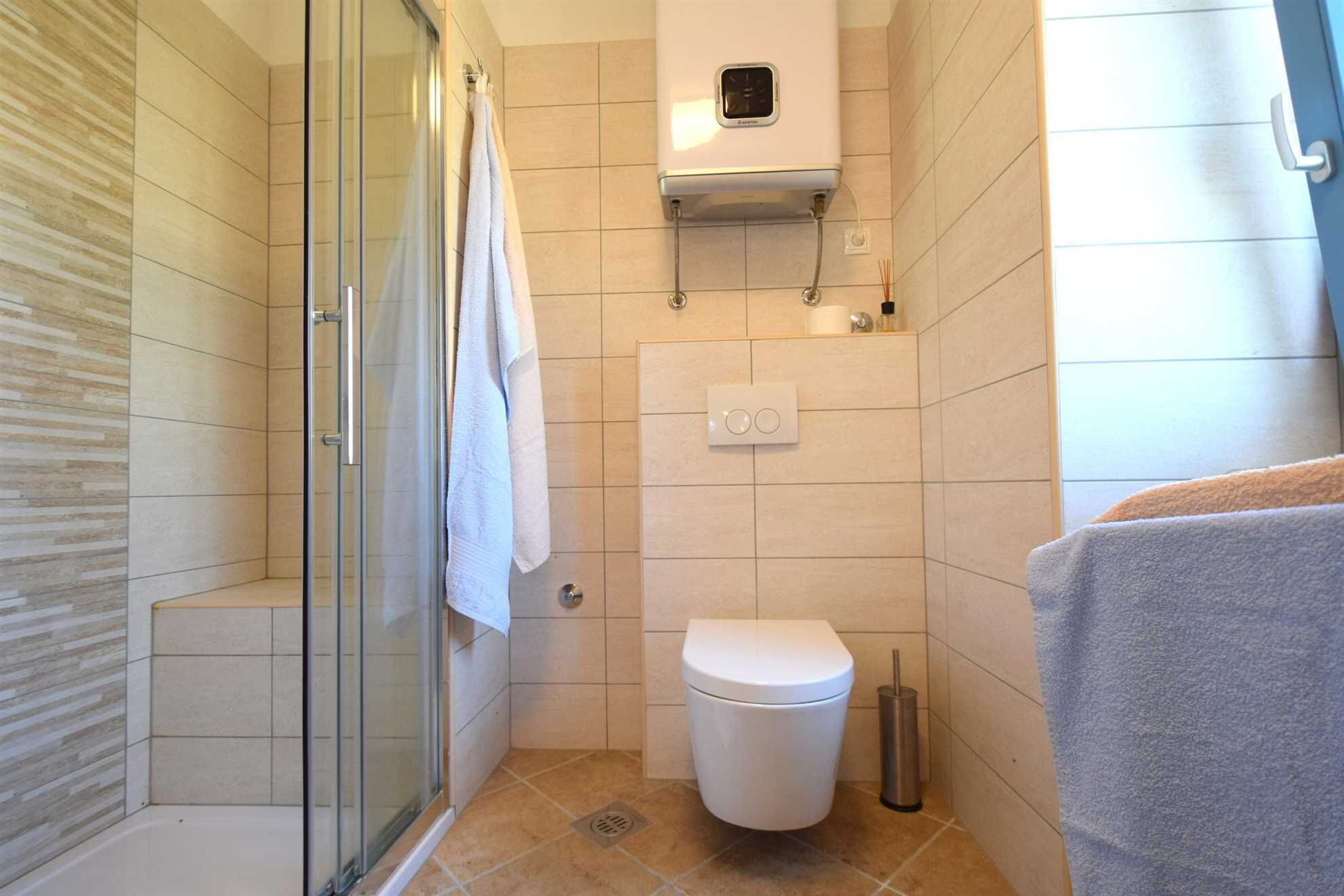 Une salle de bain moderne avec une douche à parois de verre, des toilettes et un porte-serviettes.