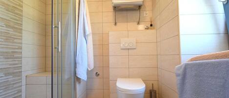 Une salle de bain moderne avec une douche à parois de verre, des toilettes et un porte-serviettes.