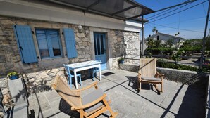 A stone building with blue shutters, a table, and two chairs in the outdoor seating area. - Studio apartment Depope 2 (Skrbčići)