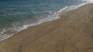 Una spiaggia con cielo sereno e luce solare che si riflette sull'acqua.