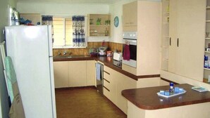 A kitchen with wooden cabinets, a refrigerator, a stove, and a sink.