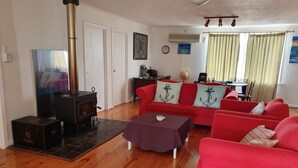A living room with a red sofa, a small table, a fireplace, and a dining area with a table and chairs.