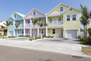 A row of three-story houses with balconies, a garage, and palm trees. - Upscale Townhouse • Heated Pool & Hot Tub • Dog-Friendly (South Padre Island)