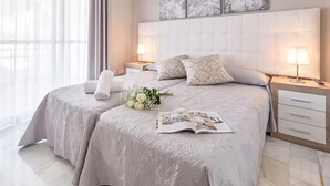 Een hotelkamer met een groot bed, twee nachtkastjes, een raam met dunne gordijnen en een luchtverfrisser aan de muur.