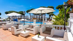 Un espace piscine sur le toit, avec des sièges et des parasols à l’extérieur.