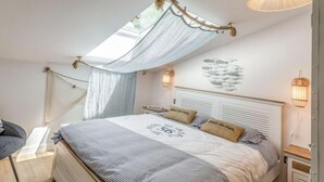 A bedroom with a bed, a canopy, a wall-mounted light, and a bedside table.