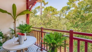 A balcony with a table, chairs, and potted plants.