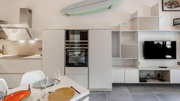 Une cuisine moderne avec des meubles blancs, un four encastré et un coin repas avec une table dressée pour deux personnes.