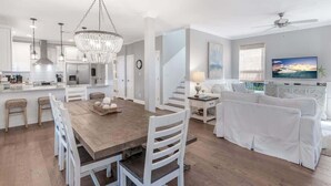 A modern kitchen with white cabinetry, a wooden dining table, and a chandelier. - Newly Redesigned, Steps to Lagoon Pool and Beach (Rosemary Beach)