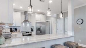 A modern kitchen with white cabinets, stainless steel appliances, and pendant lighting. - Newly Redesigned, Steps to Lagoon Pool and Beach (Rosemary Beach)